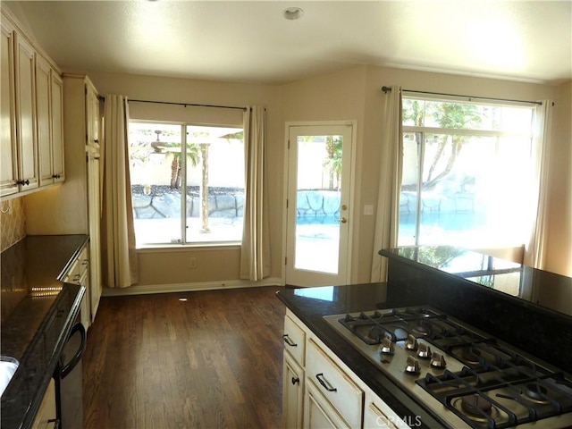 kitchen with stainless steel gas cooktop, dark wood-type flooring, dark countertops, and baseboards