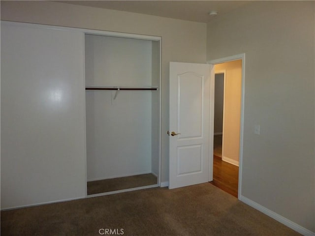 unfurnished bedroom with a closet, carpet, and baseboards