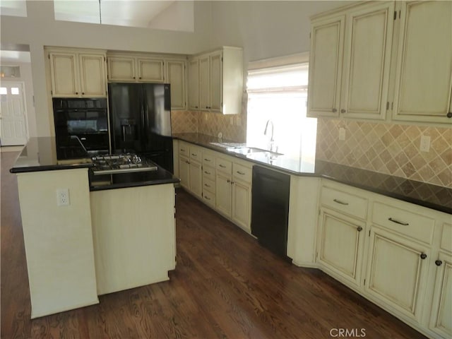 kitchen with dark wood finished floors, cream cabinetry, a sink, and black appliances