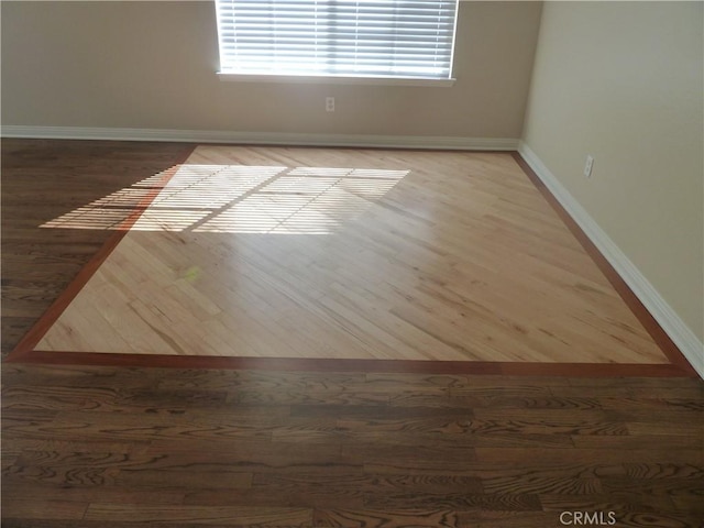 unfurnished room featuring baseboards and wood finished floors