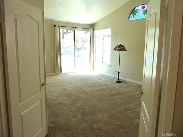 unfurnished room with lofted ceiling, carpet flooring, and baseboards