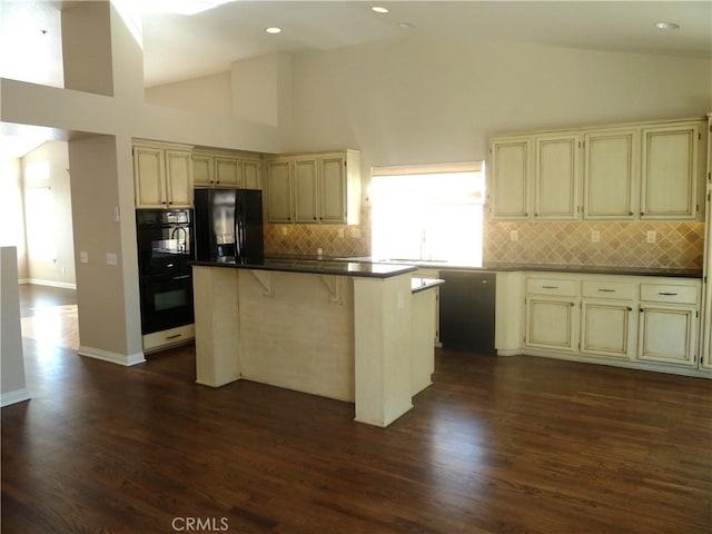 kitchen featuring cream cabinetry, a sink, a kitchen island, and black appliances