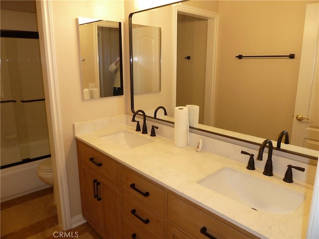 full bath with shower / bath combination, a sink, toilet, and double vanity