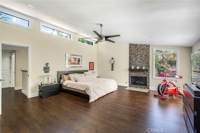 bedroom with multiple windows, a large fireplace, baseboards, and wood finished floors