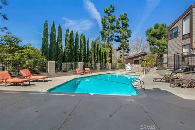 community pool with fence and a patio area