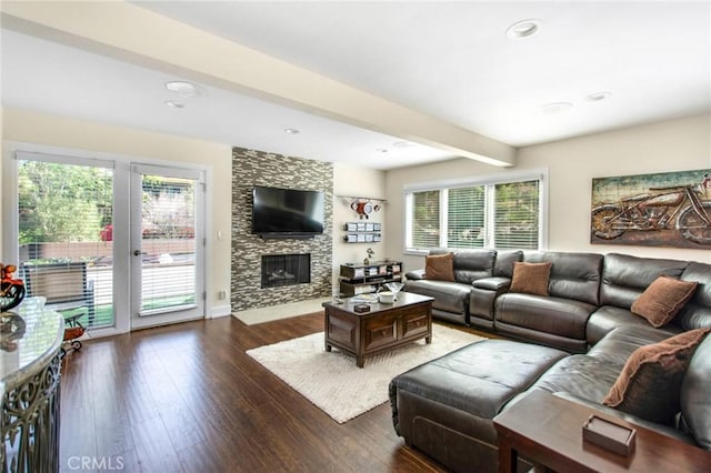 living room featuring recessed lighting, beamed ceiling, a stone fireplace, and wood finished floors