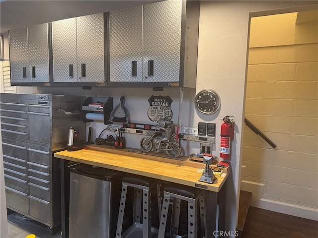 interior space featuring baseboards, wood finished floors, and concrete block wall