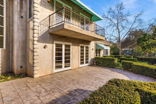 exterior space with metal roof, a patio, a balcony, and stucco siding