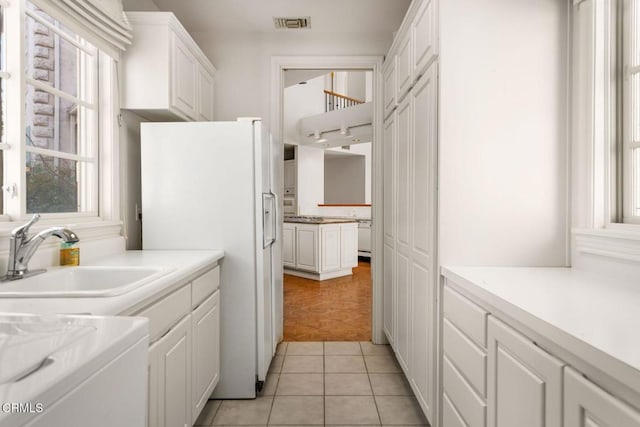 kitchen featuring white refrigerator with ice dispenser, a healthy amount of sunlight, a sink, and white cabinets