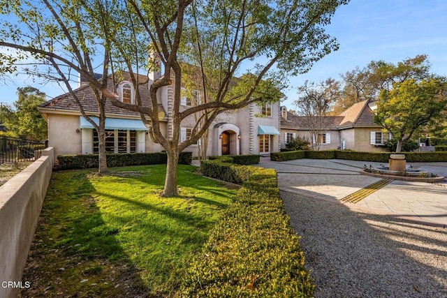 view of front of home featuring a front lawn, fence, and stucco siding