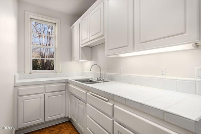 kitchen featuring white cabinets, a sink, and tile countertops