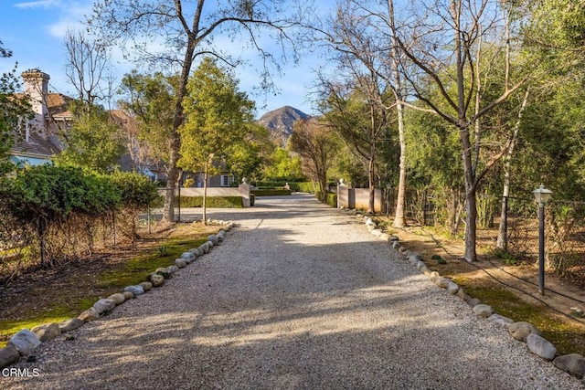 view of community with gravel driveway and fence