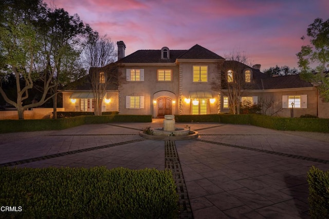 view of front of property featuring a chimney and curved driveway