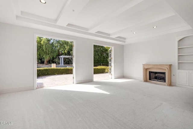 unfurnished living room featuring carpet floors, a fireplace with flush hearth, baseboards, and built in shelves