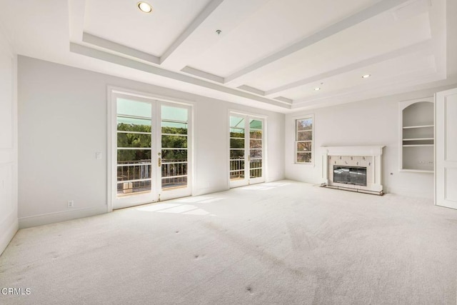 unfurnished living room with a premium fireplace, a tray ceiling, carpet flooring, and beamed ceiling