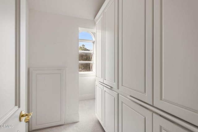 hall with baseboards and light colored carpet