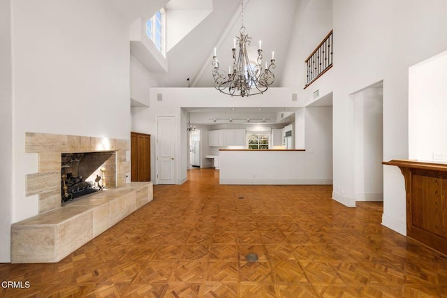 unfurnished living room with an inviting chandelier, plenty of natural light, baseboards, and a tile fireplace