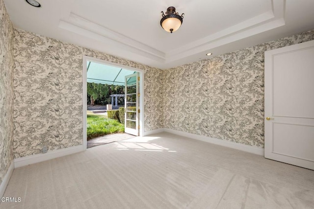 carpeted spare room with baseboards, a raised ceiling, and wallpapered walls