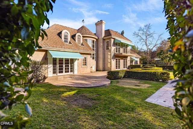 back of house with a balcony, french doors, a lawn, stucco siding, and a patio area