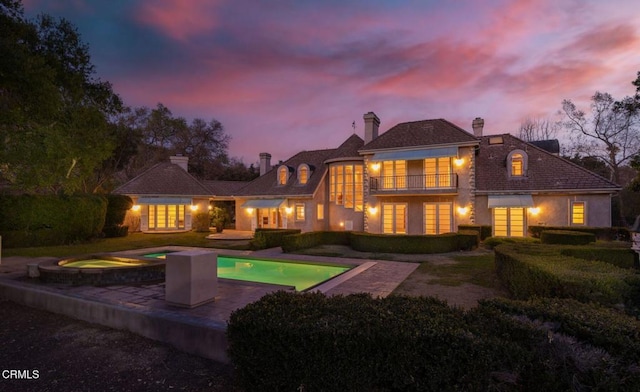 508 W Eucalyptus St, Ojai, CA 93023 - back of property at dusk featuring a balcony, a chimney, a patio area, stucco siding, and a pool with connected hot tub