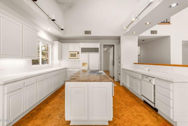 508 W Eucalyptus St, Ojai, CA 93023 - kitchen featuring built in appliances, a center island, white cabinetry, decorative backsplash, and light stone counters