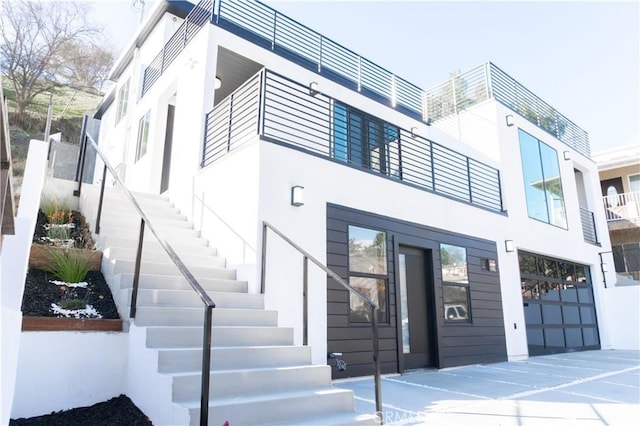 view of front facade with a garage, stairway, and stucco siding