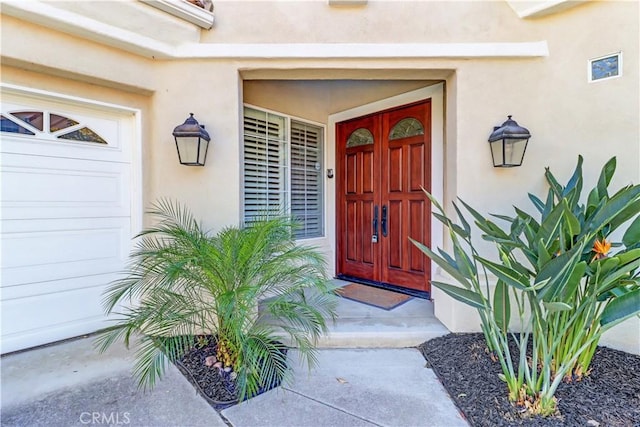 entrance to property featuring an attached garage and stucco siding