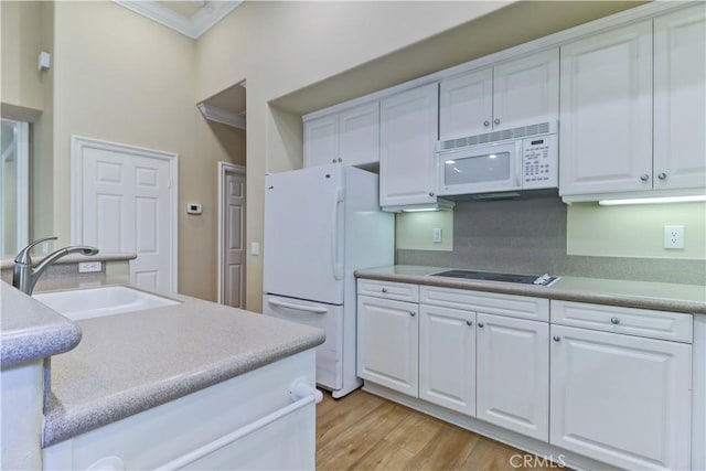 kitchen featuring white appliances, a sink, white cabinets, ornamental molding, and light wood finished floors