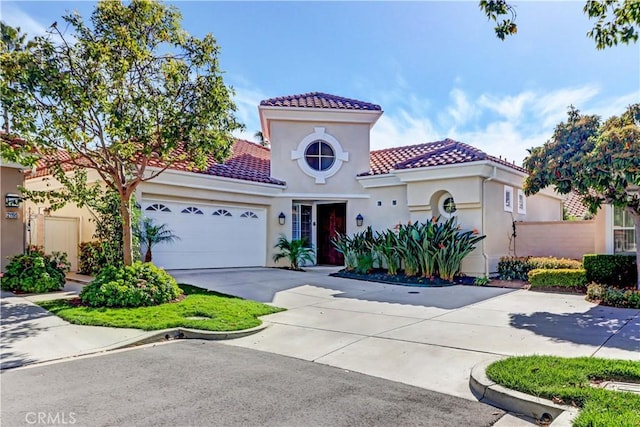 mediterranean / spanish-style home featuring driveway, a tiled roof, an attached garage, and stucco siding