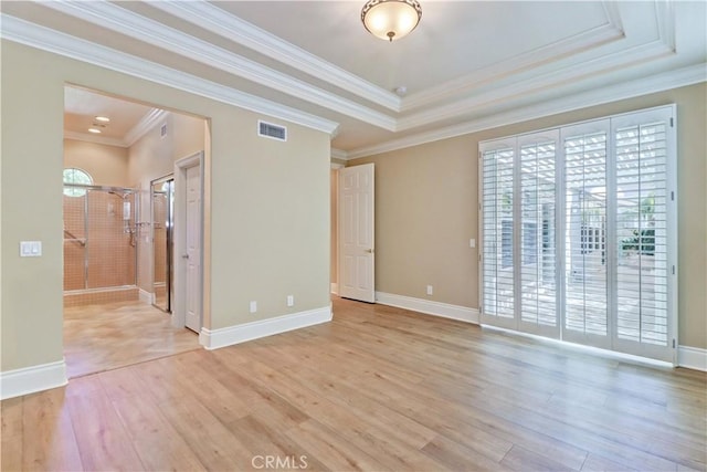 empty room with light wood-type flooring, visible vents, crown molding, and baseboards