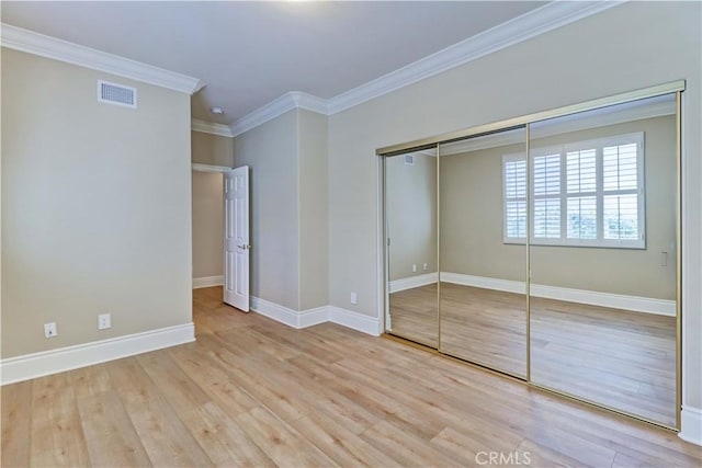 unfurnished bedroom with crown molding, a closet, visible vents, and wood finished floors