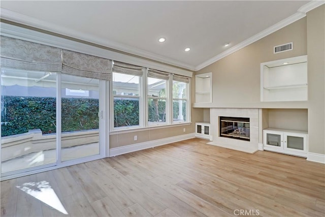 unfurnished living room featuring crown molding, visible vents, a tiled fireplace, vaulted ceiling, and wood finished floors