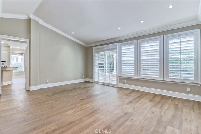 empty room featuring baseboards, light wood-style floors, and crown molding