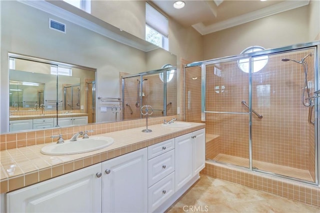 full bath featuring double vanity, visible vents, ornamental molding, a sink, and a shower stall