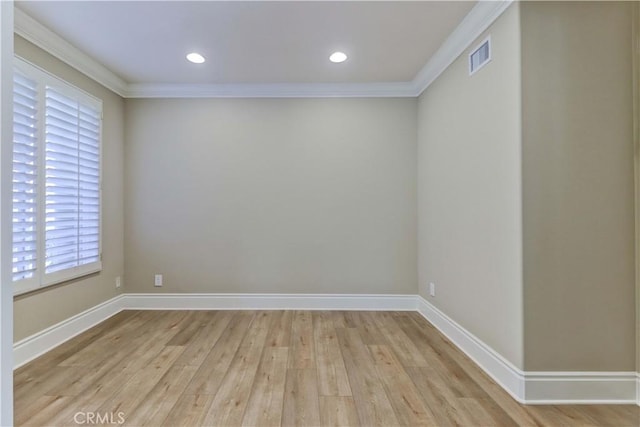 spare room featuring ornamental molding, baseboards, visible vents, and light wood finished floors