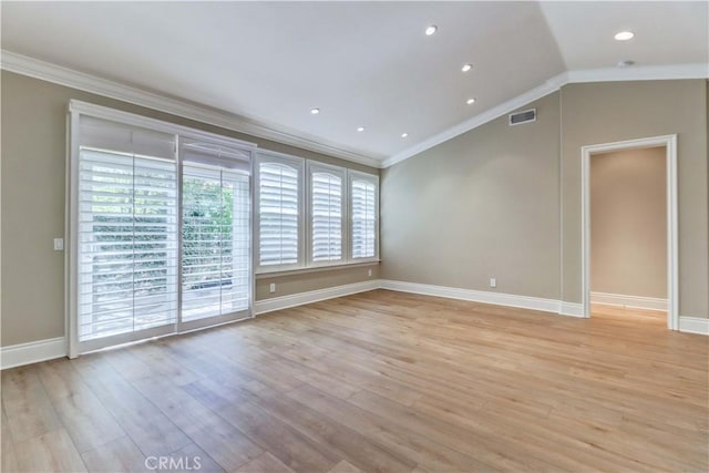 spare room featuring light wood-type flooring, vaulted ceiling, crown molding, and baseboards