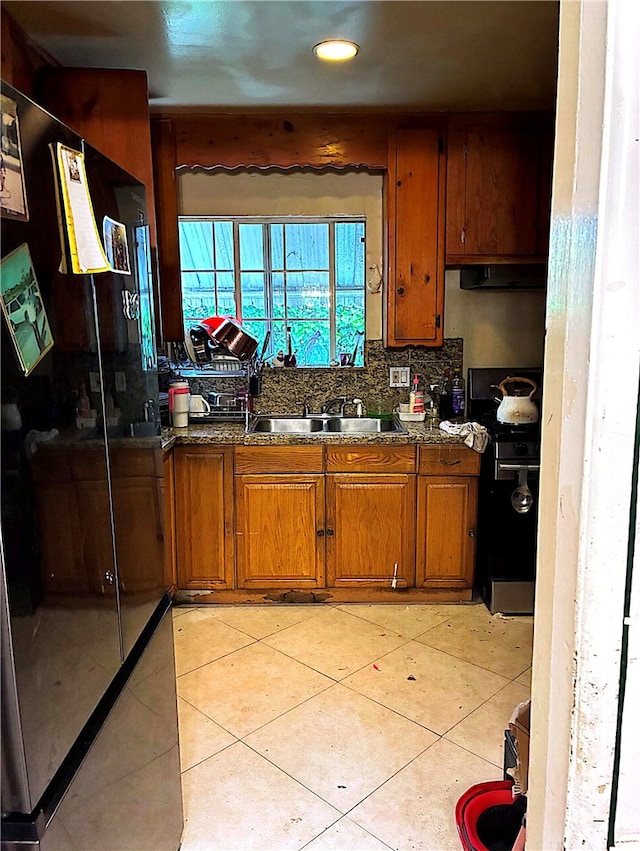 kitchen with range, brown cabinetry, under cabinet range hood, and a sink