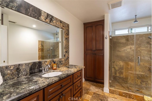 bathroom featuring stone finish flooring, a stall shower, vanity, and visible vents