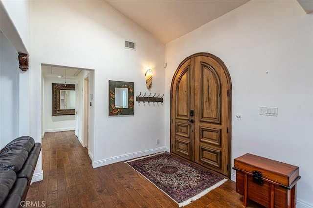 foyer with arched walkways, vaulted ceiling, dark wood-style floors, and visible vents