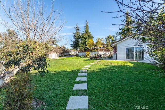 view of yard featuring a storage unit, fence, and an outbuilding