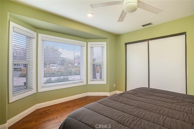 bedroom with wood finished floors, visible vents, baseboards, and multiple windows