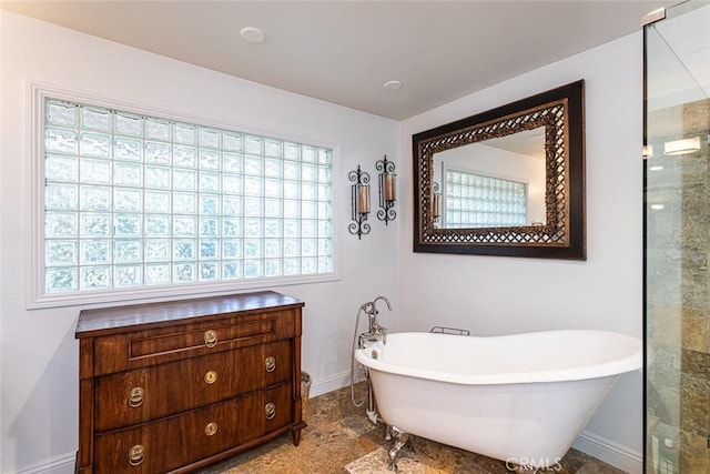 full bathroom with a freestanding tub, baseboards, and a shower with shower door