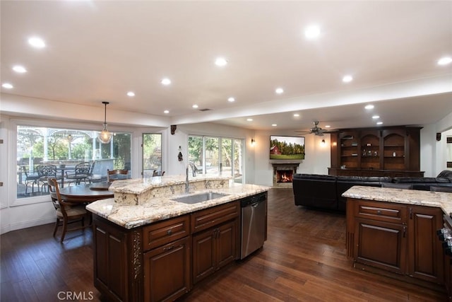 kitchen featuring a sink, open floor plan, stainless steel dishwasher, an island with sink, and dark wood finished floors