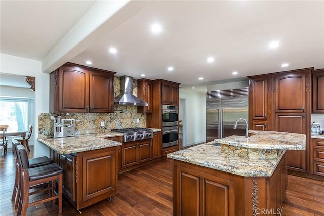 kitchen with dark wood-style floors, wall chimney exhaust hood, stainless steel appliances, and a sink