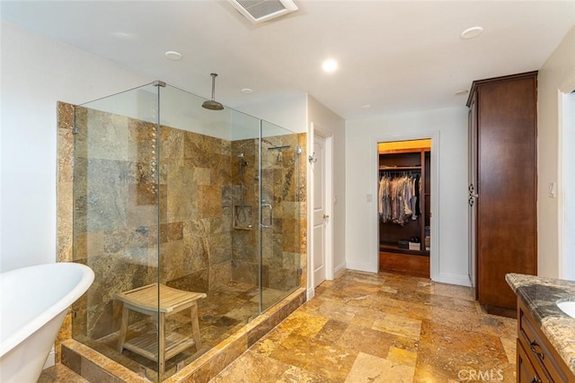 full bath featuring a freestanding tub, vanity, visible vents, a shower stall, and stone finish flooring