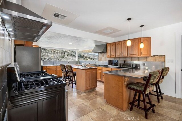 kitchen featuring a peninsula, visible vents, ventilation hood, backsplash, and black gas range oven