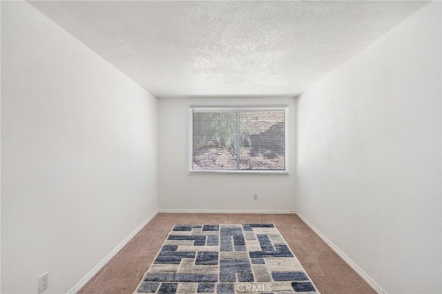 unfurnished room with carpet, baseboards, and a textured ceiling