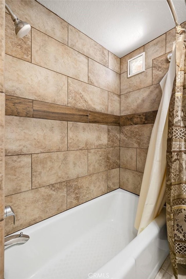 full bathroom with a textured ceiling and shower / tub combo with curtain