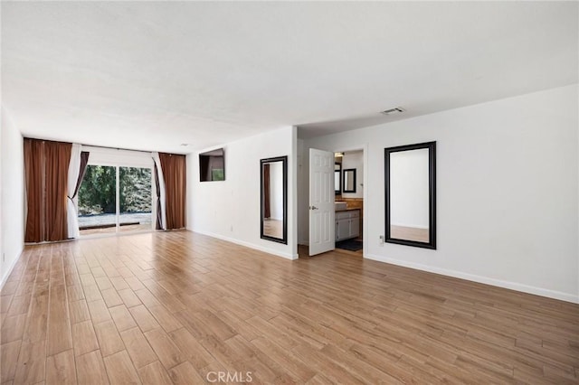 unfurnished room featuring light wood-style flooring, visible vents, and baseboards