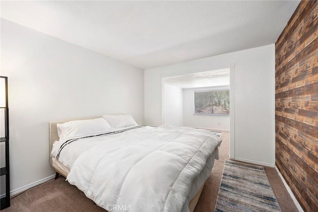 bedroom with carpet, wooden walls, and baseboards